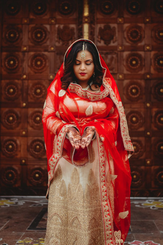 Indian wedding bride showing her henna painted hands to the photographer